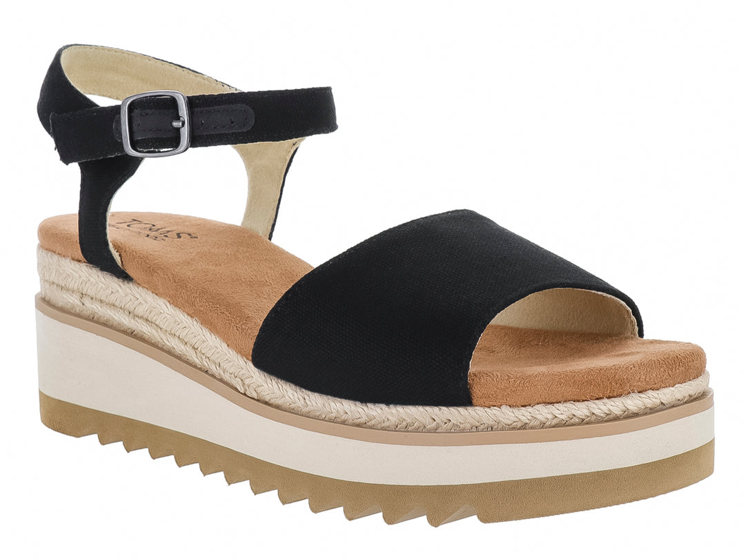 Sandalia de plataforma TOMS color negro con suela blanca y detalle de esparto en la cuña.
