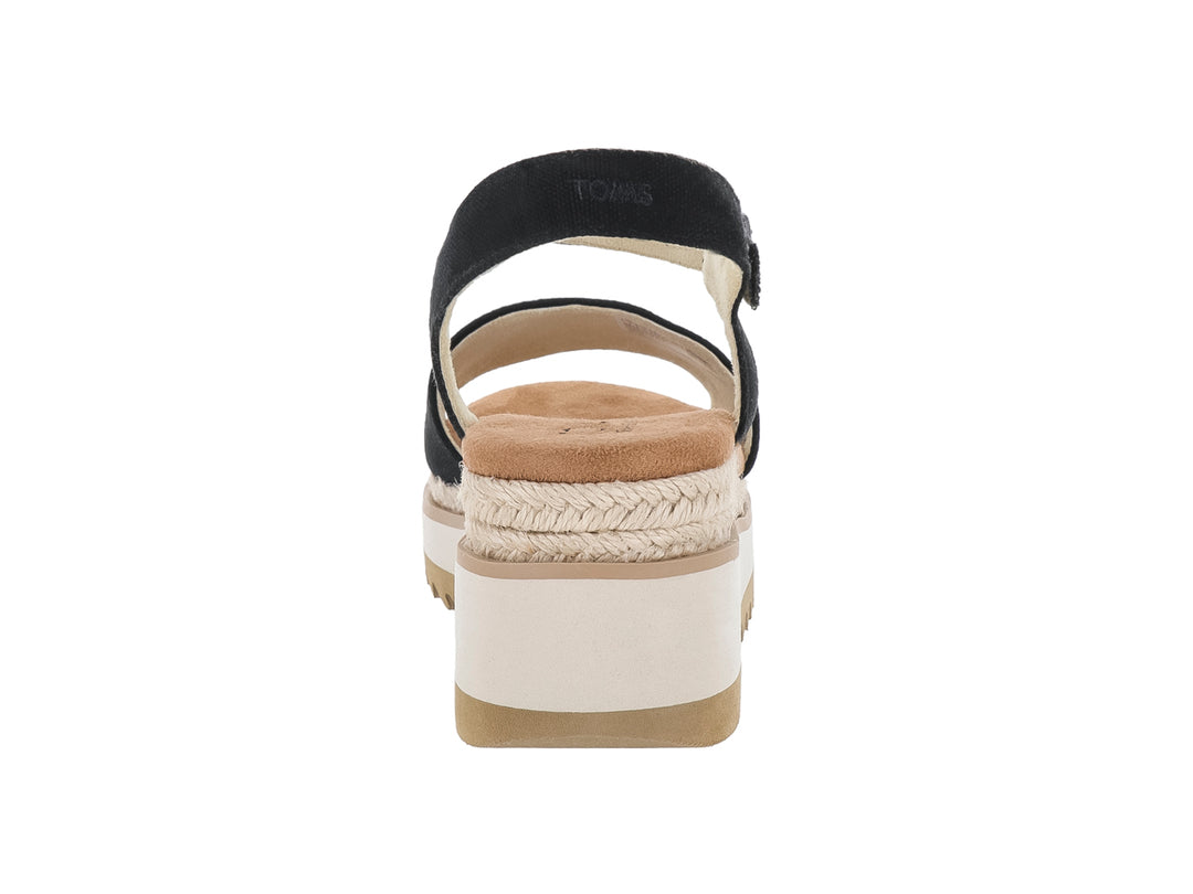Sandalia de plataforma TOMS color negro con suela blanca y detalle de esparto en la cuña.