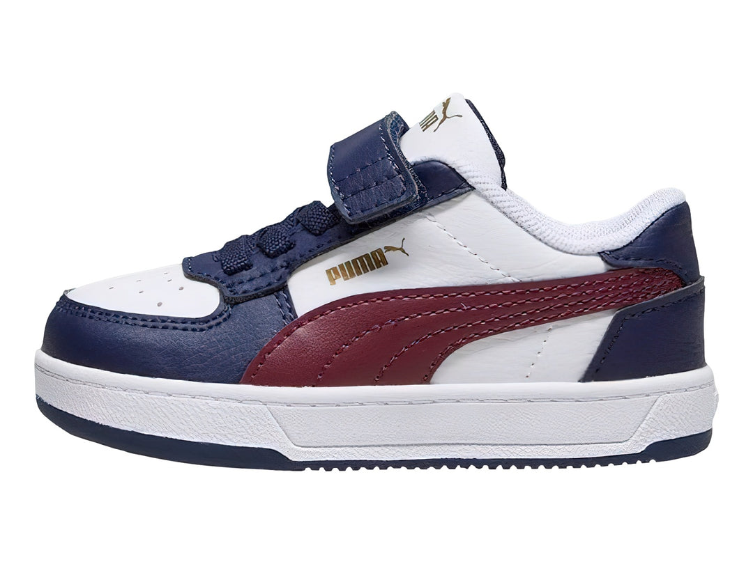 Tenis PUMA infantiles en colores blanco y azul marino con franja roja y cierre de velcro.
