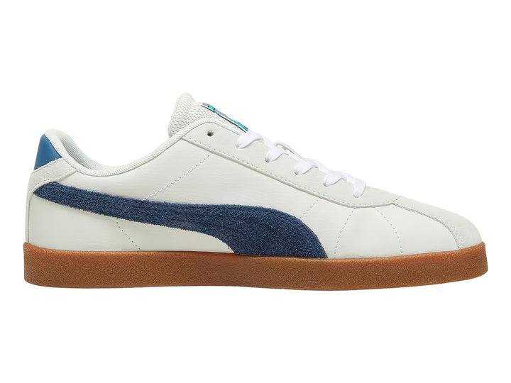 Tenis PUMA blancos con franja azul marino y suela de goma color café.