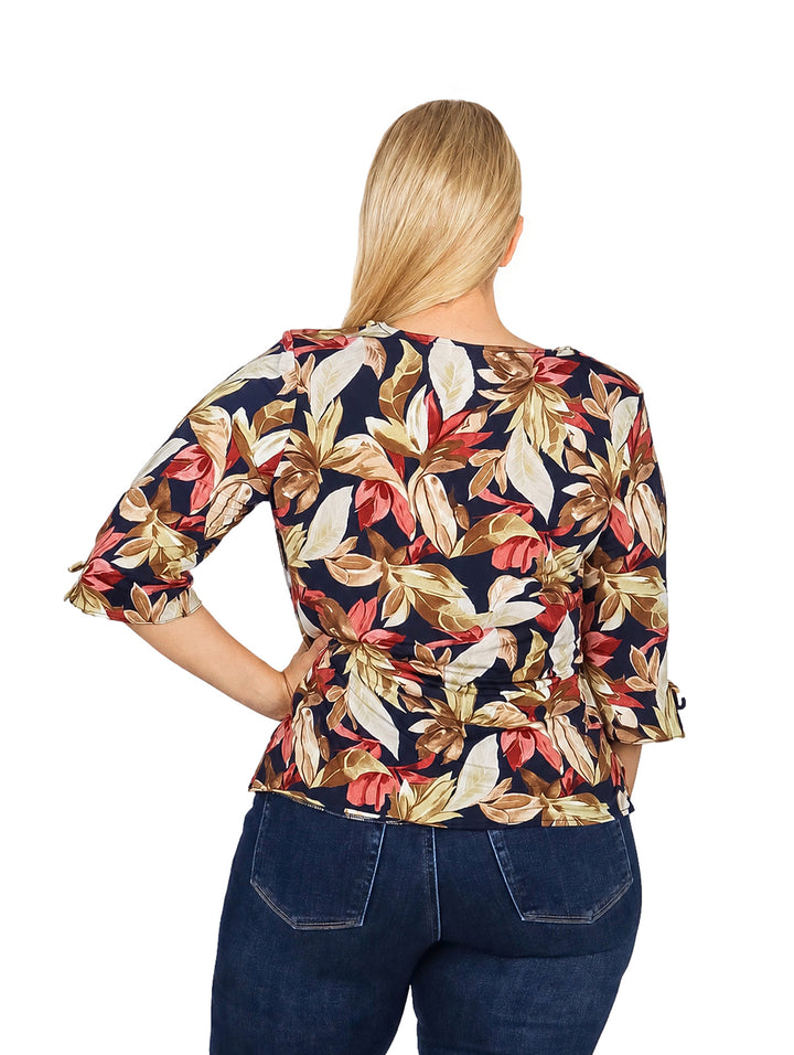 Mujer vistiendo blusa multicolor con estampado floral y mangas 3/4.