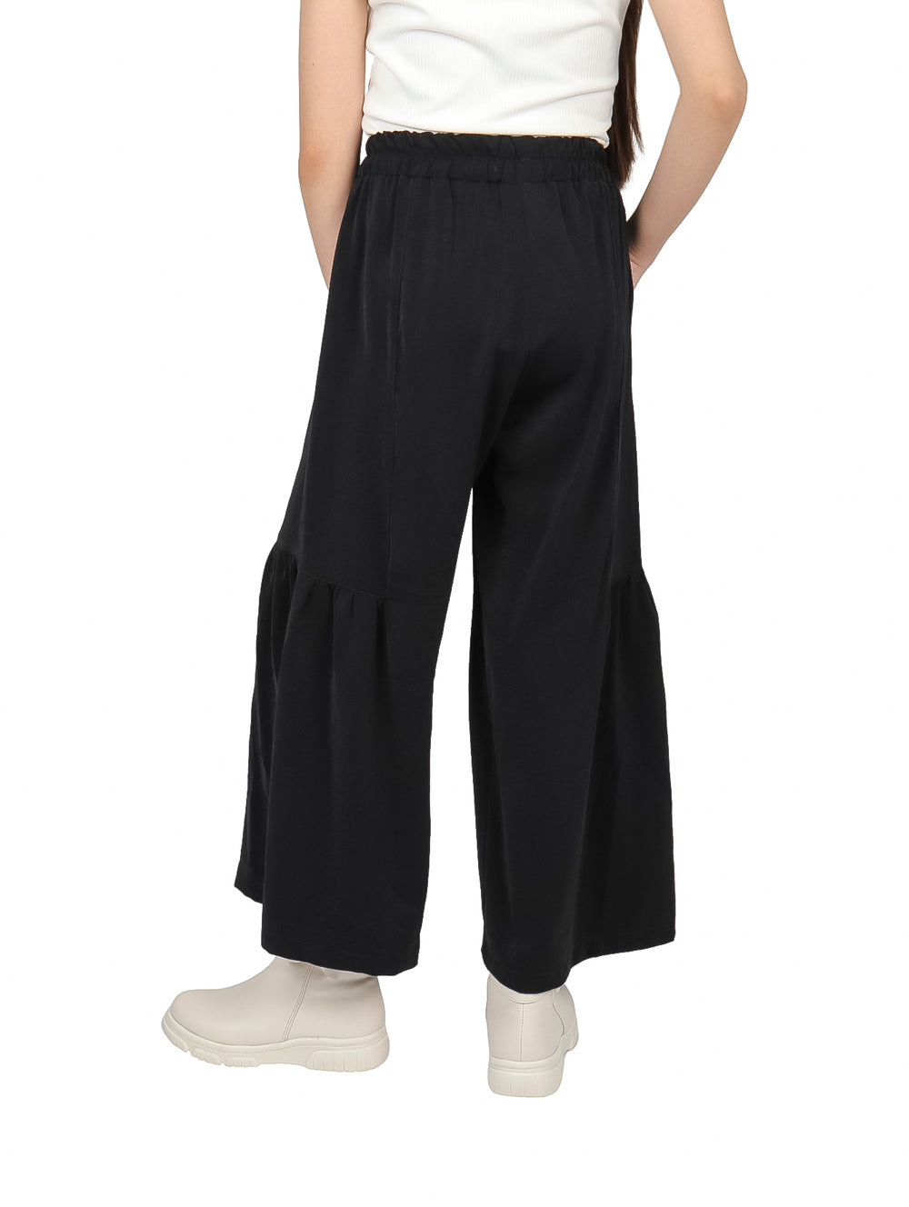 Niña vistiendo pantalón negro de pierna ancha con cintura elástica y botas blancas.