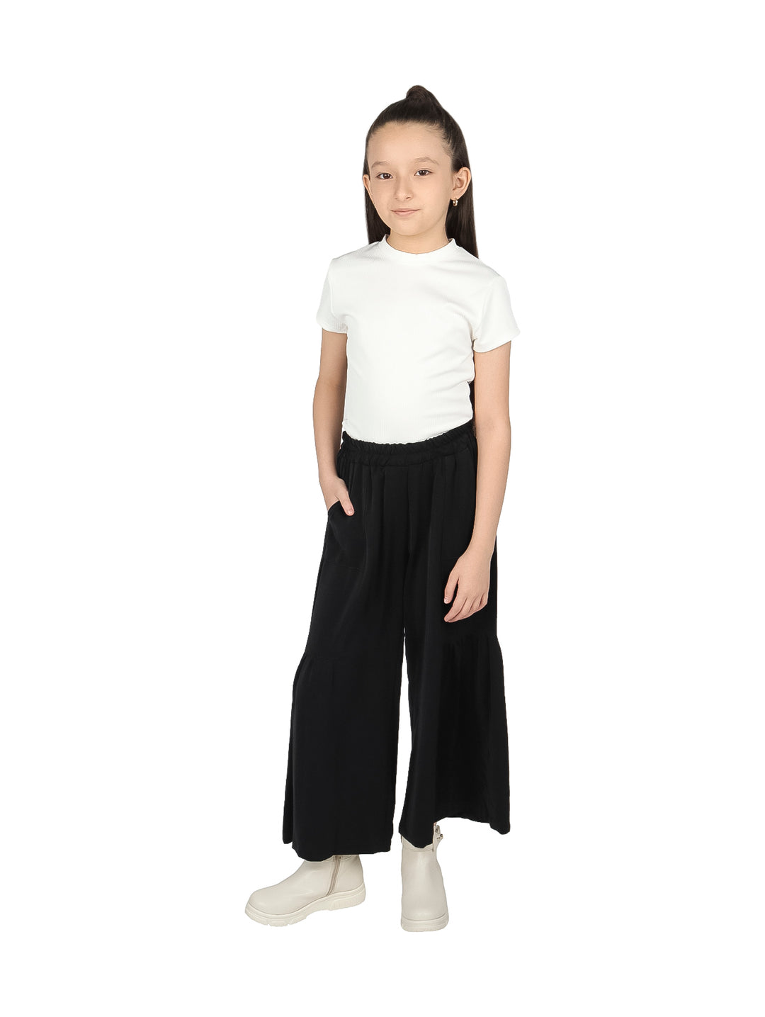Niña vistiendo pantalón negro de pierna ancha con cintura elástica y botas blancas.