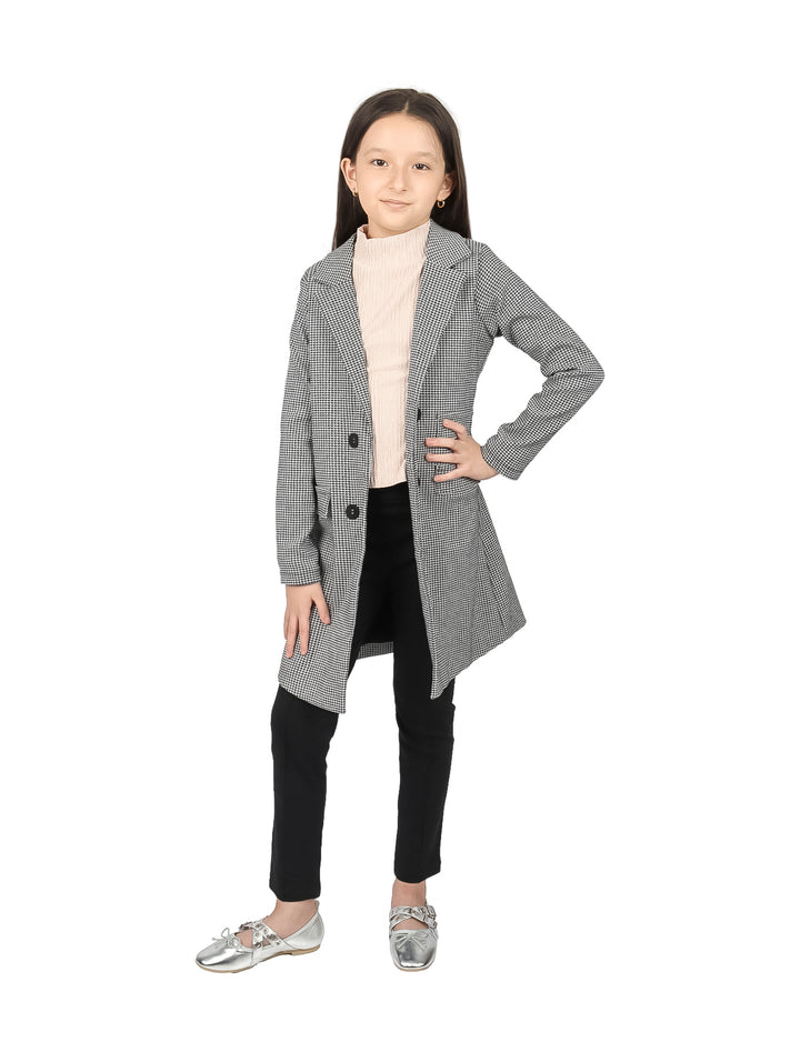 Niña vistiendo un blazer largo de color negro y blanco con estampado de cuadros y botones frontales.