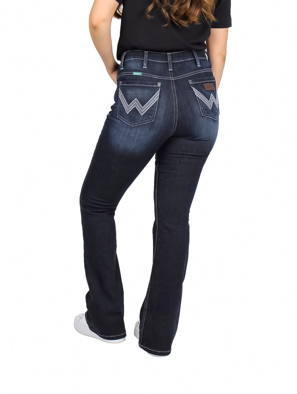 Mujer vistiendo jeans Wrangler Western de color negro con corte recto y tenis blancos.