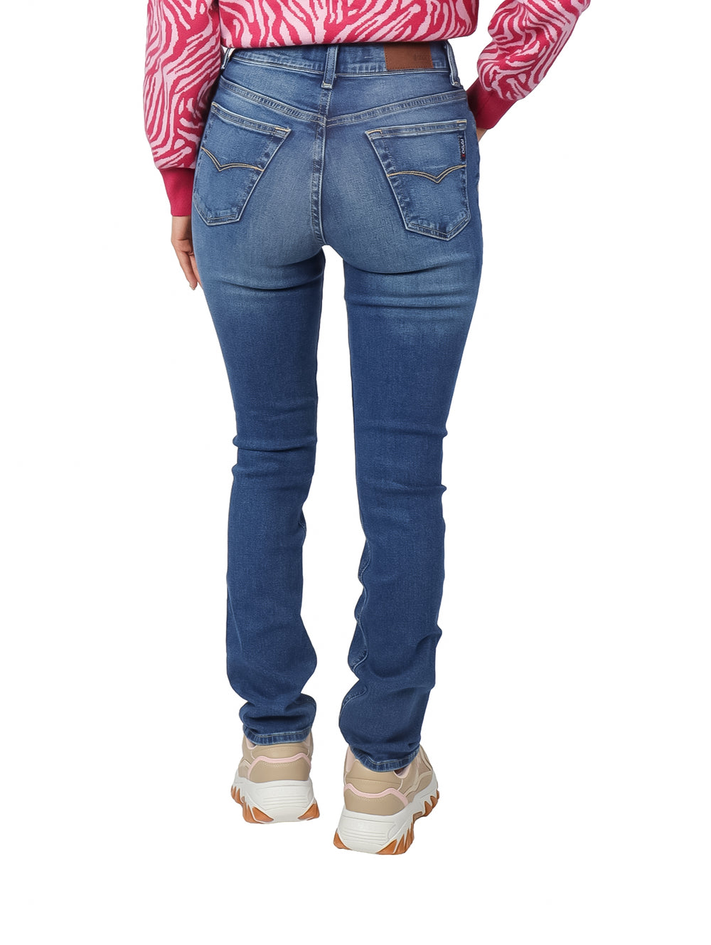 Mujer vistiendo pantalones jeans rectos de color azul con efecto vintage y tenis beige.