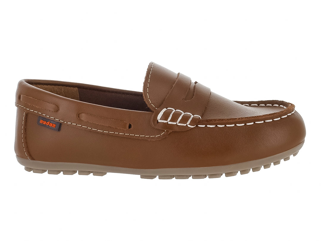 Zapato tipo mocasín color café para Niño con costuras blancas y suela dentada.