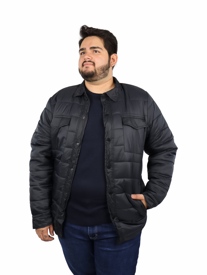 Hombre usando una chamarra negra acolchada con botones y bolsillos frontales.