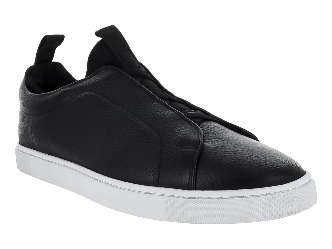 Zapato tipo slip-on de piel negra con suela blanca y pestaña trasera para calce fácil.