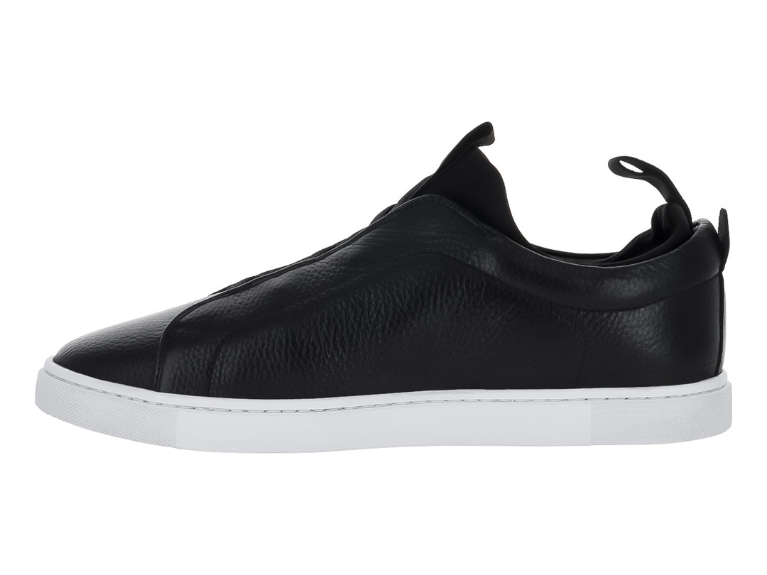 Zapato tipo slip-on de piel negra con suela blanca y pestaña trasera para calce fácil.
