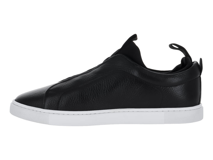 Zapato tipo slip-on de piel negra con suela blanca y pestaña trasera para calce fácil.