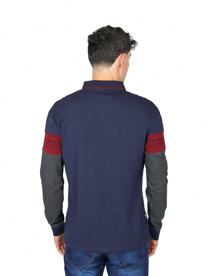 Hombre vistiendo playera polo de manga larga con bloques de color azul marino, guinda y gris carbón.