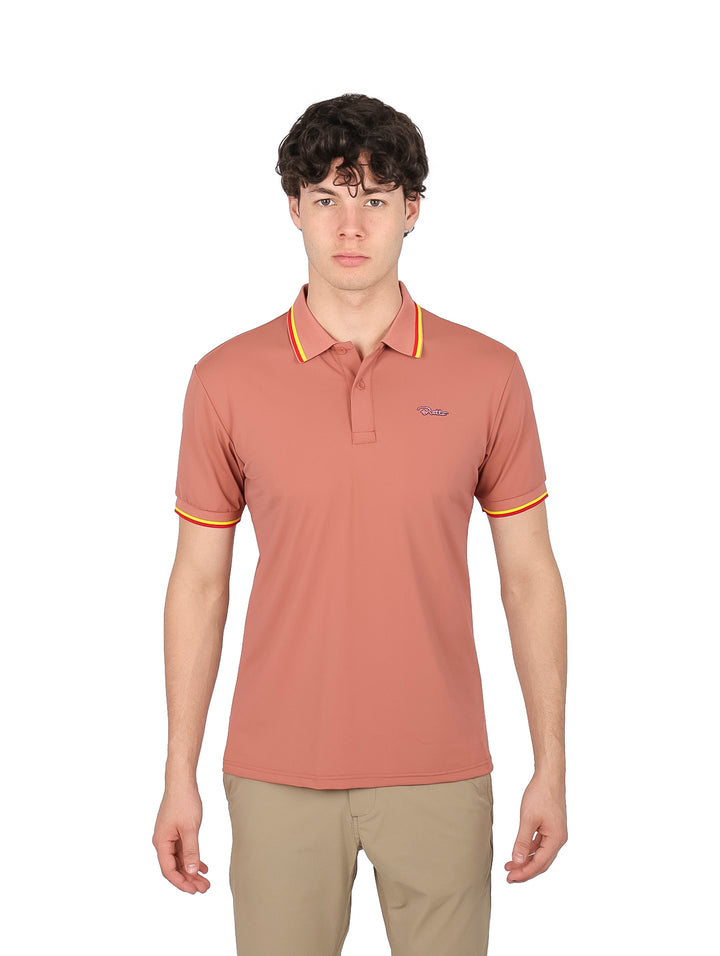 Hombre vistiendo playera polo color marrón con detalles amarillos y rojos en el cuello y mangas.