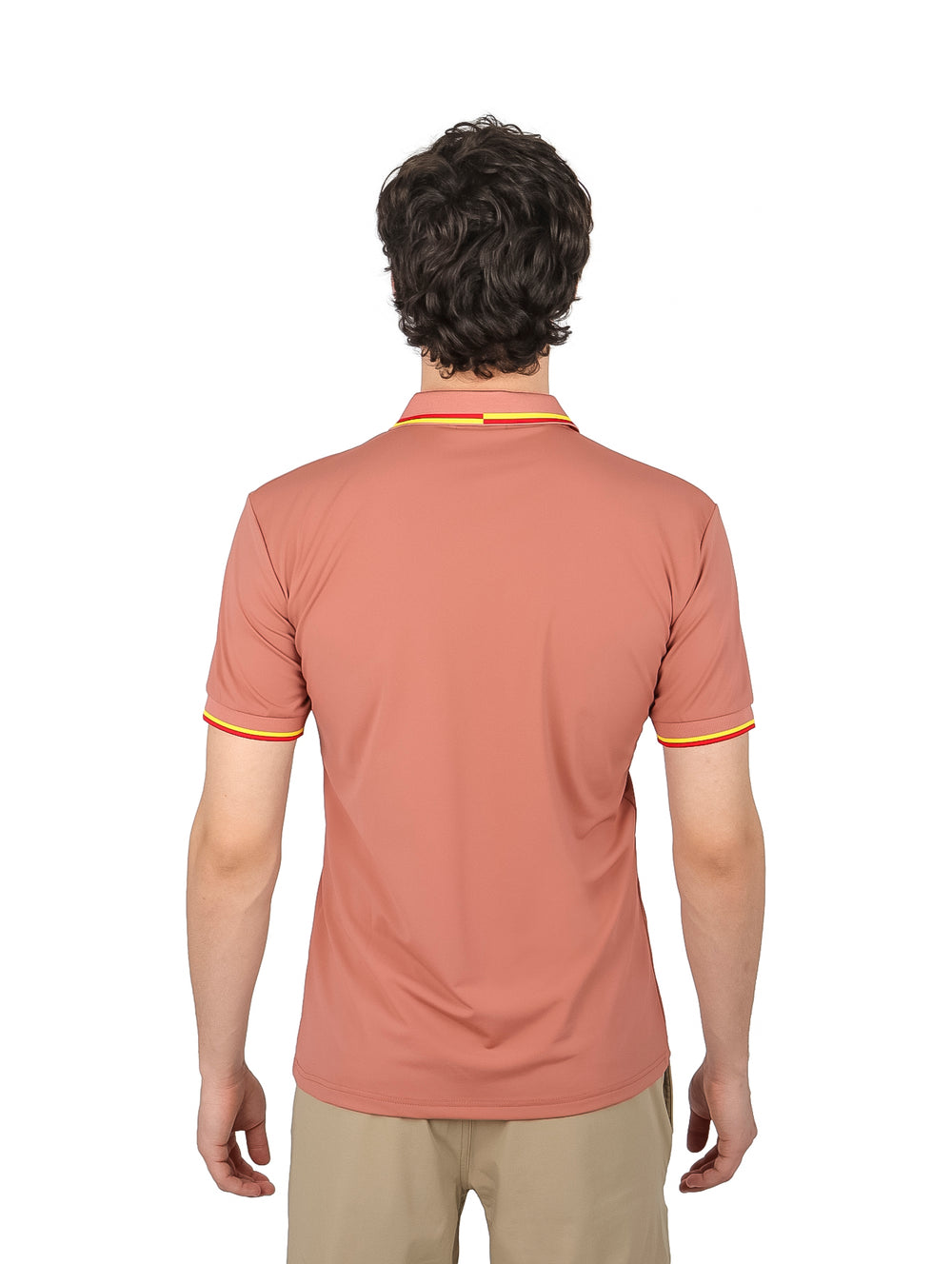 Hombre vistiendo playera polo color marrón con detalles amarillos y rojos en el cuello y mangas.