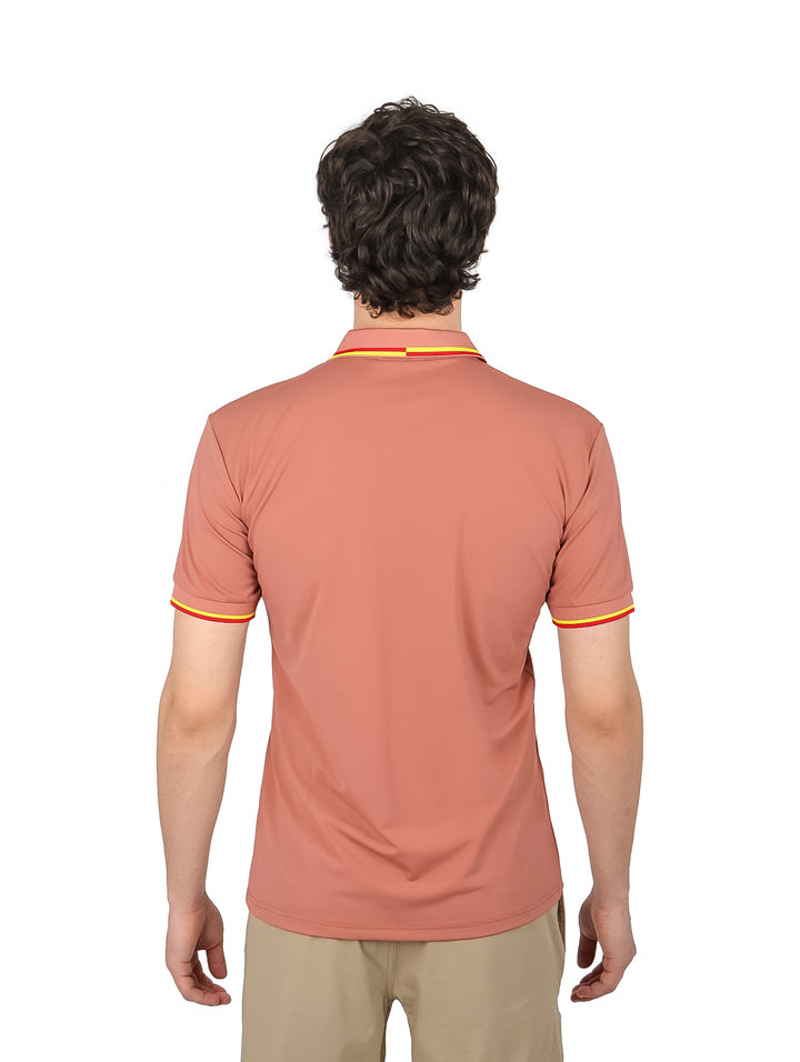 Hombre vistiendo playera polo color marrón con detalles amarillos y rojos en el cuello y mangas.