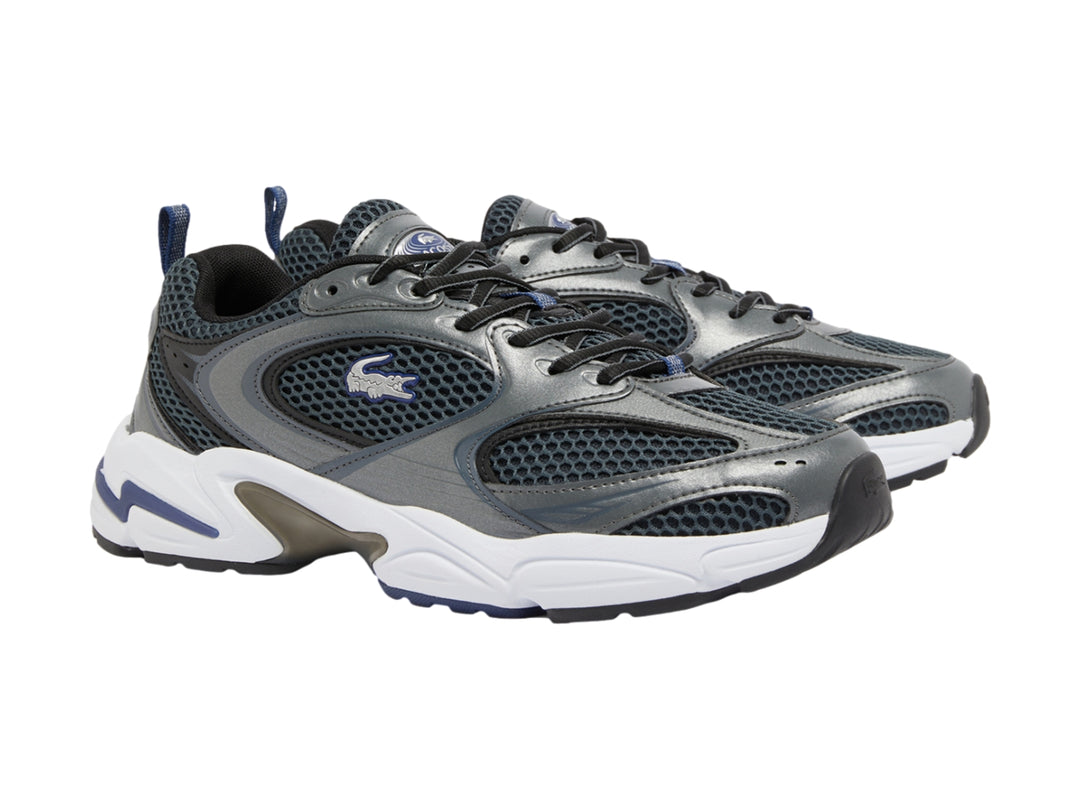 Tenis deportivos Lacoste en color gris oscuro y azul marino con suela blanca robusta.