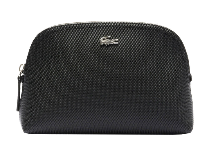 Bolso pequeño de color negro con textura granulada y logotipo metálico de Lacoste en el centro.