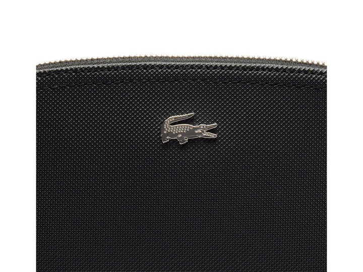 Bolso pequeño de color negro con textura granulada y logotipo metálico de Lacoste en el centro.