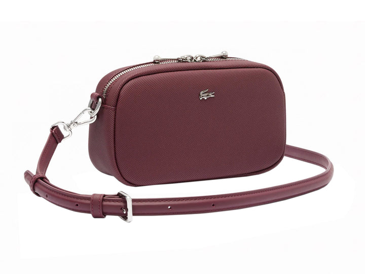 Bolso bandolera Lacoste color tinto con textura granulada, cierre superior y correa ajustable.
