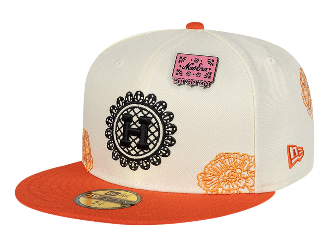 Gorra New Era blanca con visera naranja y detalles de parches y bordados decorativos.
