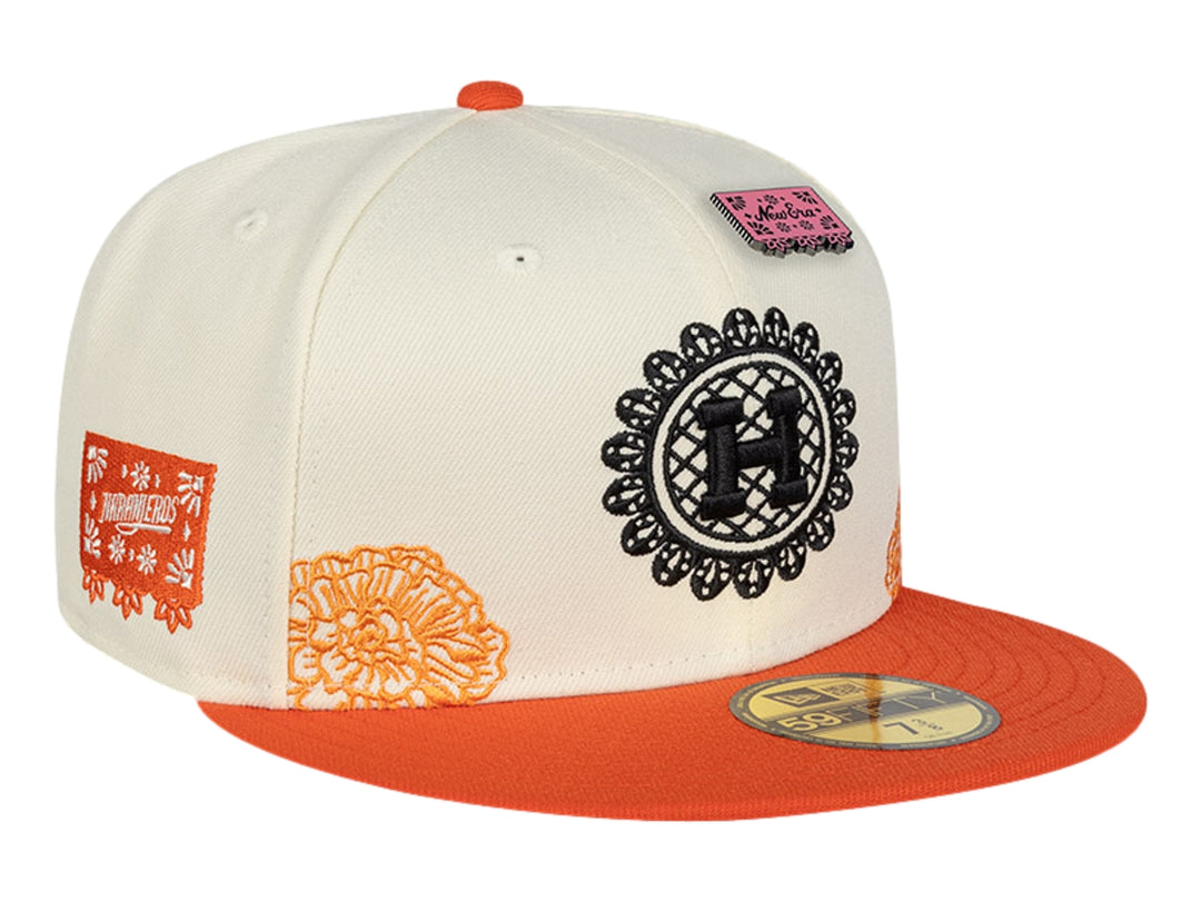 Gorra New Era blanca con visera naranja y detalles de parches y bordados decorativos.