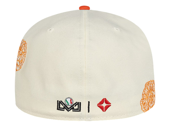 Gorra New Era blanca con visera naranja y detalles de parches y bordados decorativos.