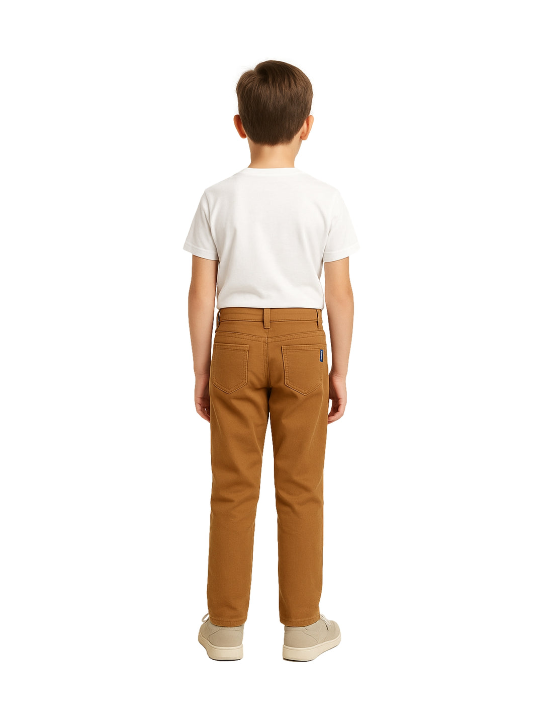 Niño modelando un pantalón casual color tabaco con camiseta blanca y tenis beige.