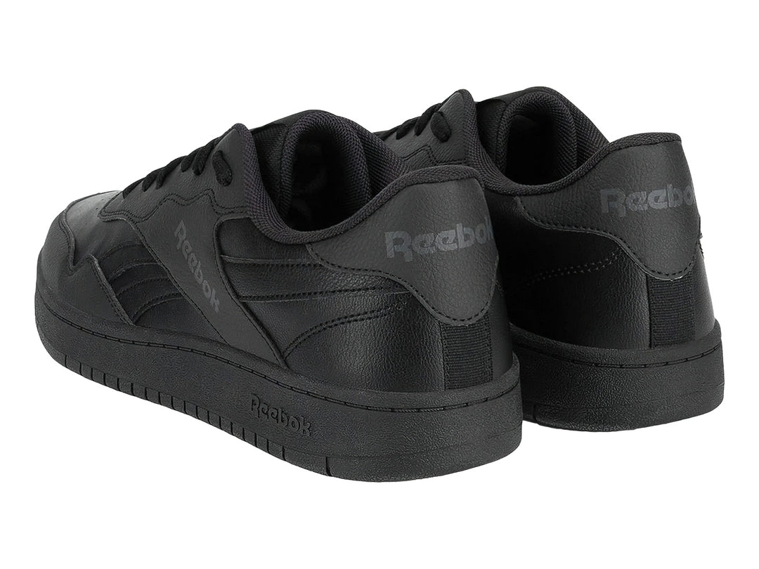 Tenis Reebok color negro con suela plana y cordones, vista lateral.