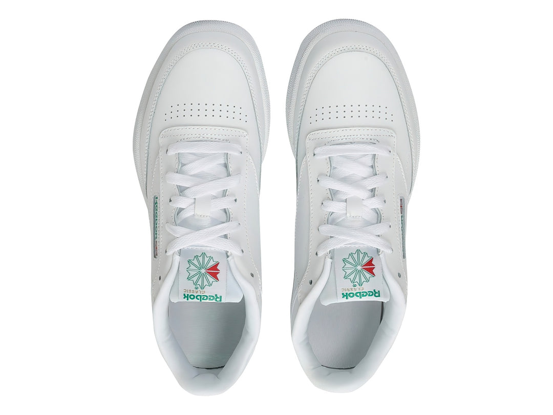 Tenis Reebok Club C blancos con detalles verdes y suela blanca.