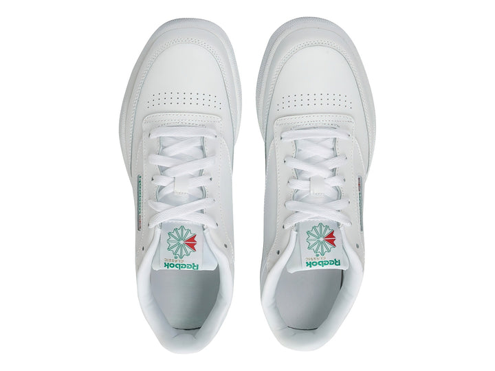 Tenis Reebok Club C blancos con detalles verdes y suela blanca.