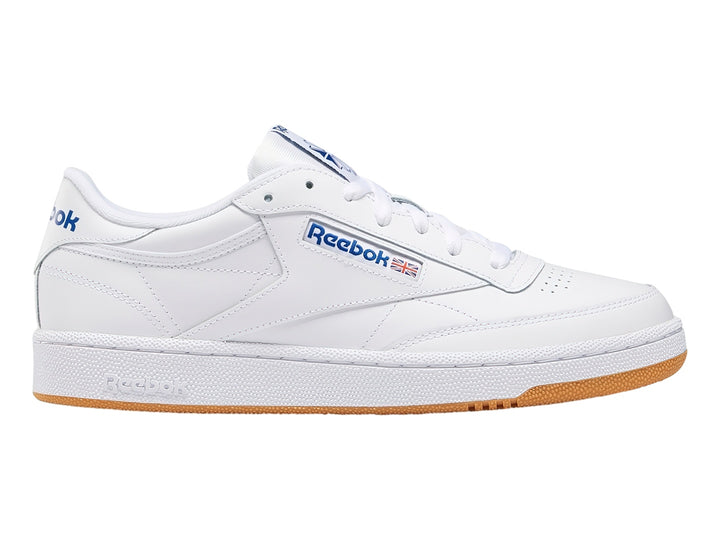 Tenis Reebok Club C 85 blancos con suela de goma marrón y detalles en azul.