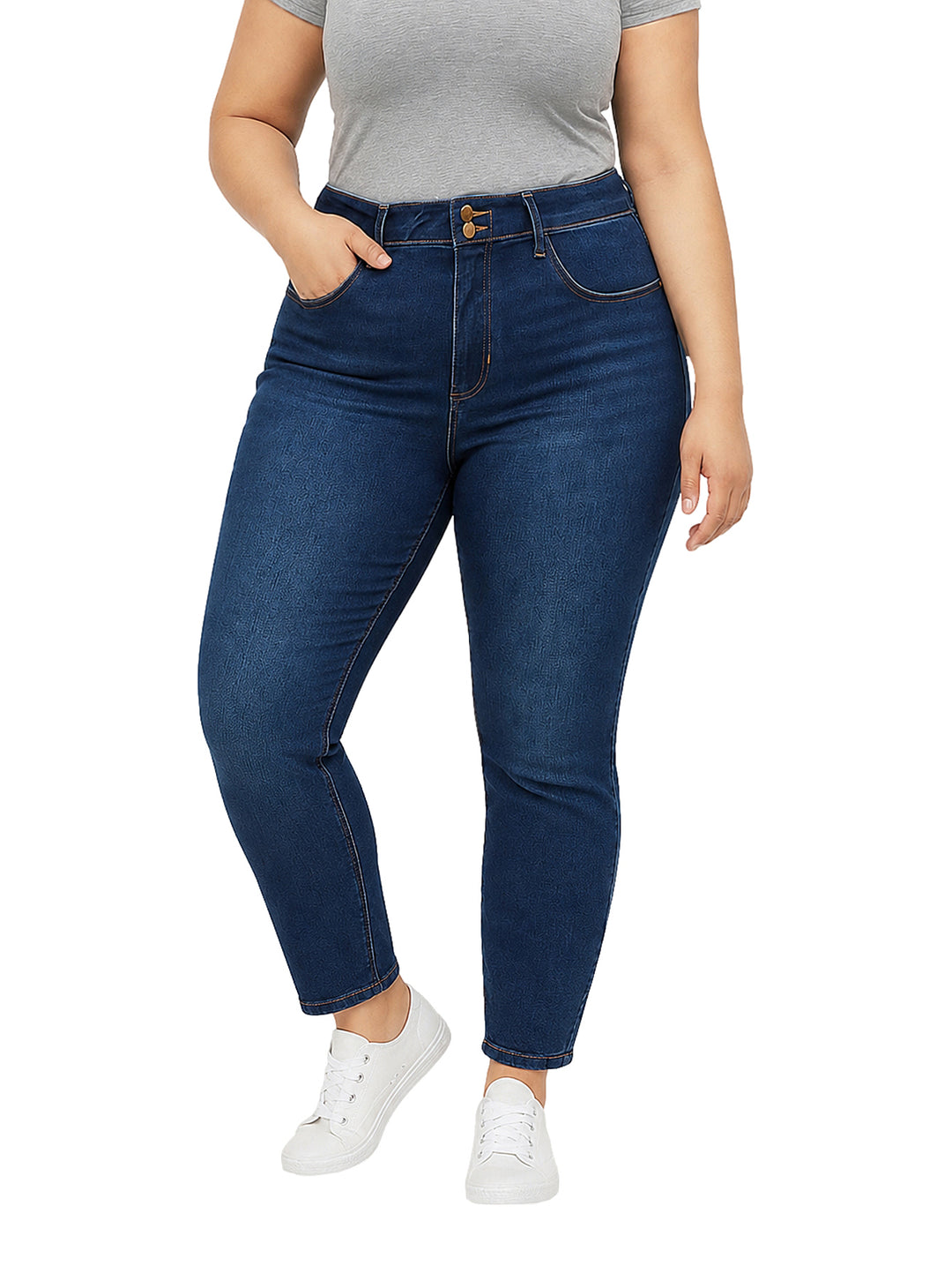 Mujer vistiendo pantalones jeans skinny de color azul oscuro con costuras doradas y tenis blancos.