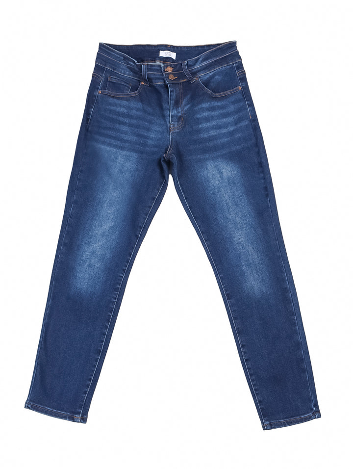 Mujer vistiendo pantalones jeans skinny de color azul oscuro con costuras doradas y tenis blancos.