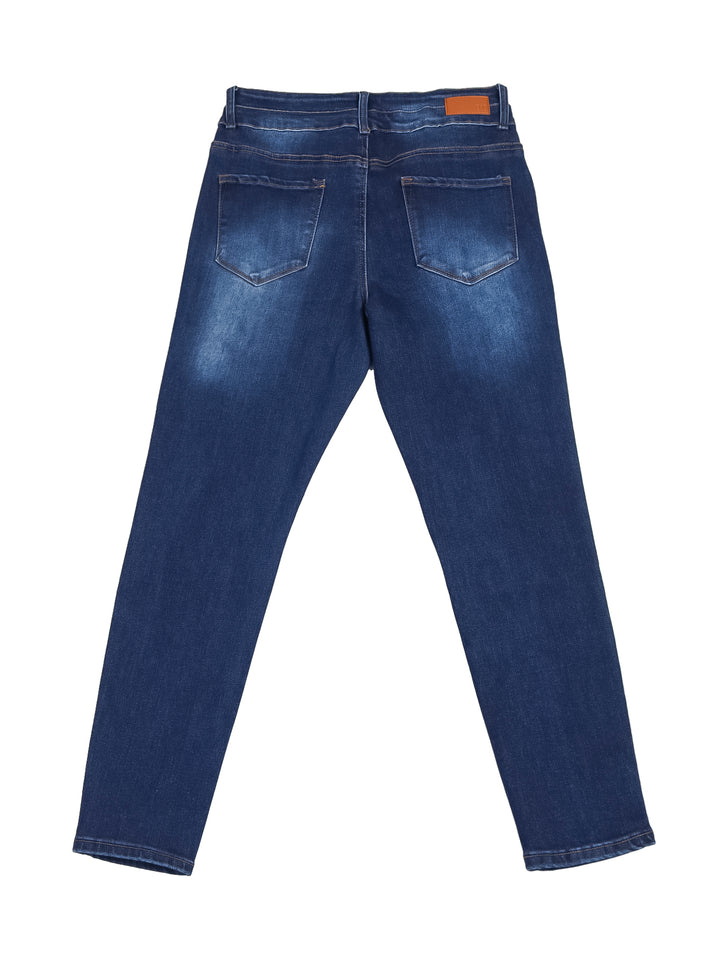 Mujer vistiendo pantalones jeans skinny de color azul oscuro con costuras doradas y tenis blancos.
