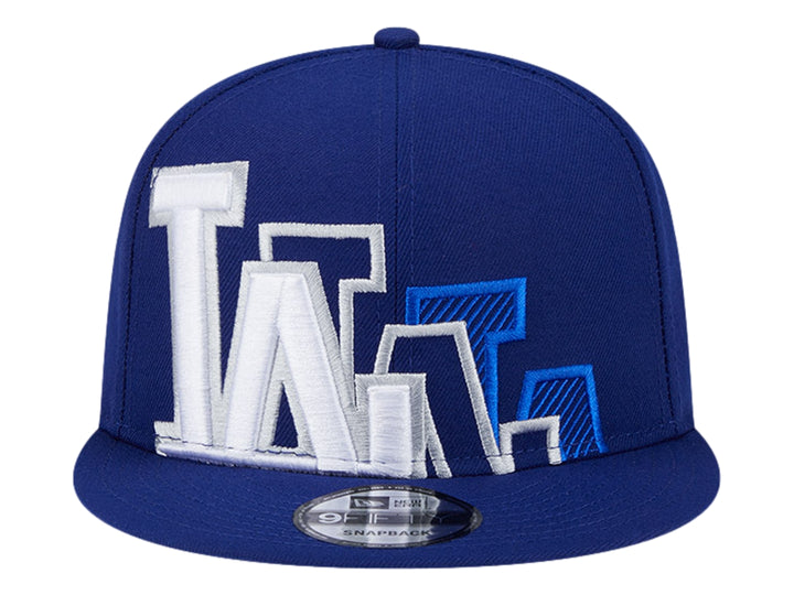 Gorra New Era azul con visera plana y diseño gráfico bordado en blanco y azul en el frente.