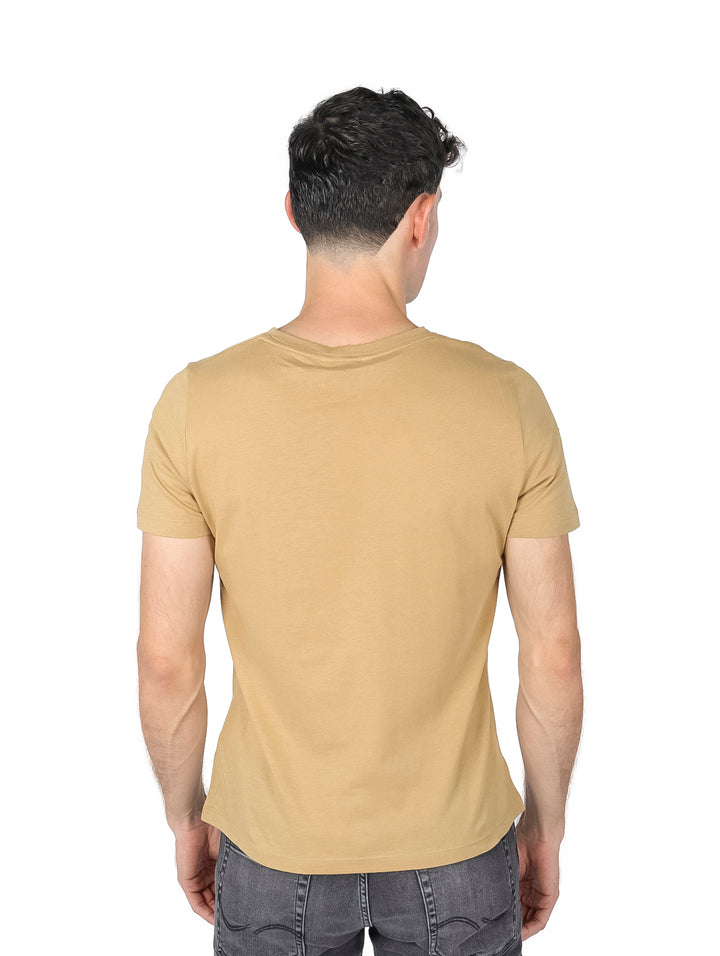 Hombre vistiendo una camiseta de color khaki con el logo de Tommy Hilfiger en el pecho.