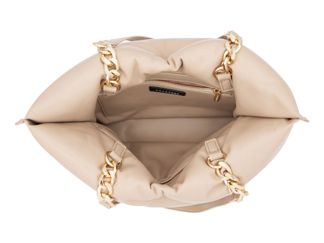 Bolsa de hombro color beige con detalles de cadena dorada y logotipo Crabtree en la parte inferior.