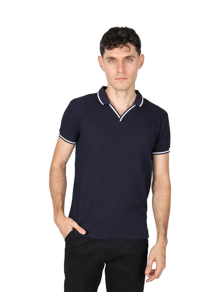 Hombre vistiendo playera polo color negro con detalles blancos en el cuello y mangas.