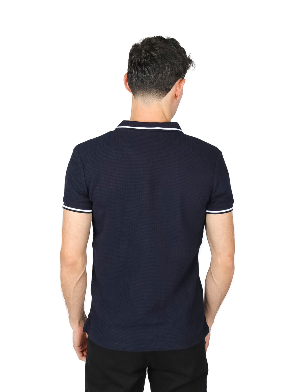 Hombre vistiendo playera polo color negro con detalles blancos en el cuello y mangas.