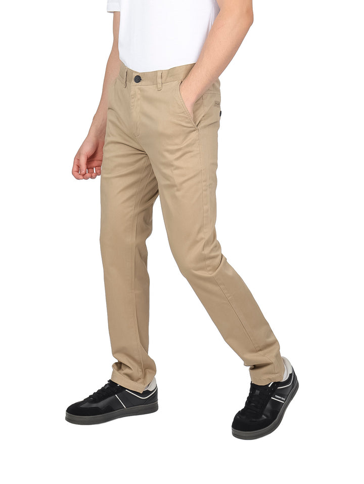 Hombre vistiendo un pantalón casual de color beige con corte recto y calzado negro.