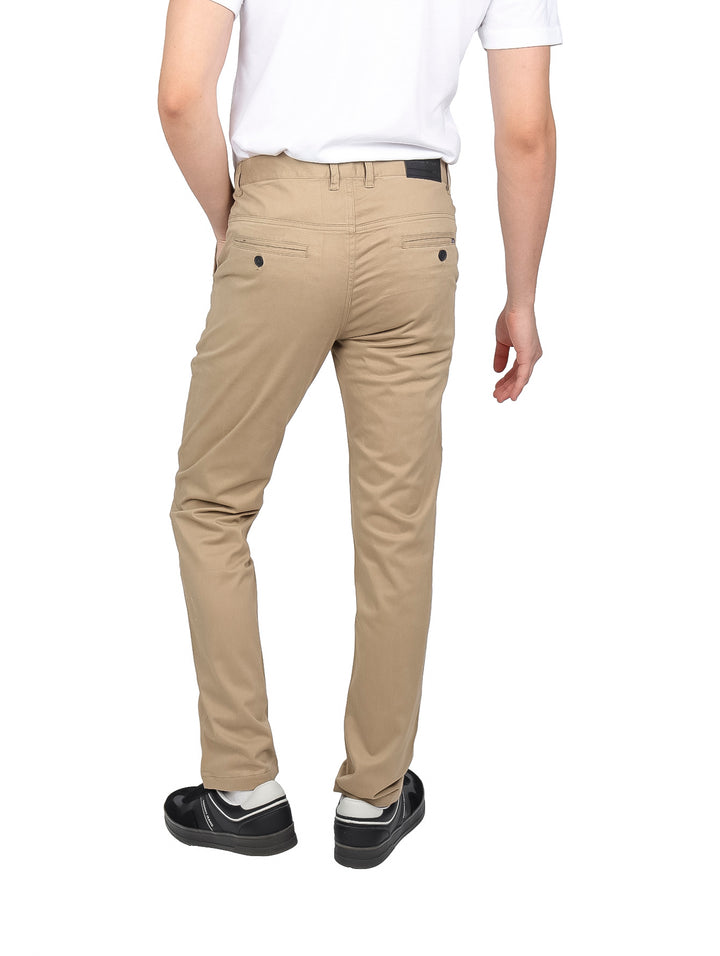 Hombre vistiendo un pantalón casual de color beige con corte recto y calzado negro.