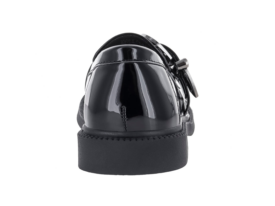 Zapato tipo mocasín para niño en color negro brillante con hebilla decorativa plateada.