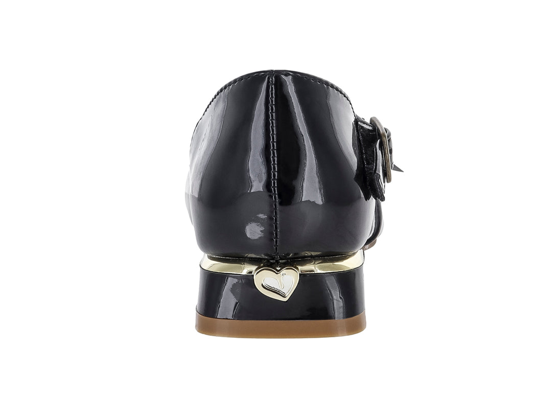 Zapato negro de charol para niña con moño decorativo, pedrerías y correa ajustable al tobillo.