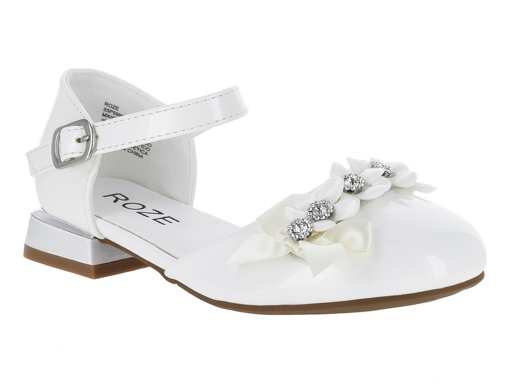 Zapato blanco brillante para niña con detalle de flor y pedrería en la punta y correa ajustable al tobillo.