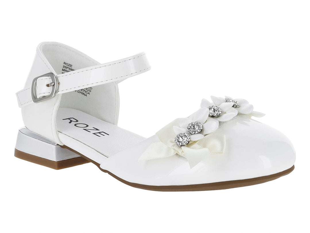 Zapato blanco brillante para niña con detalle de flor y pedrería en la punta y correa ajustable al tobillo.