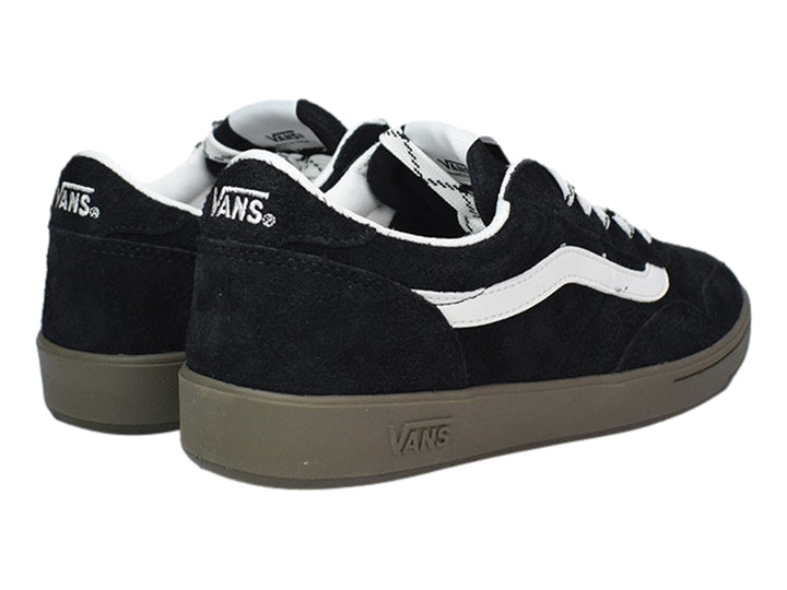 Tenis VANS negros de gamuza con franja lateral blanca y suela color marrón.