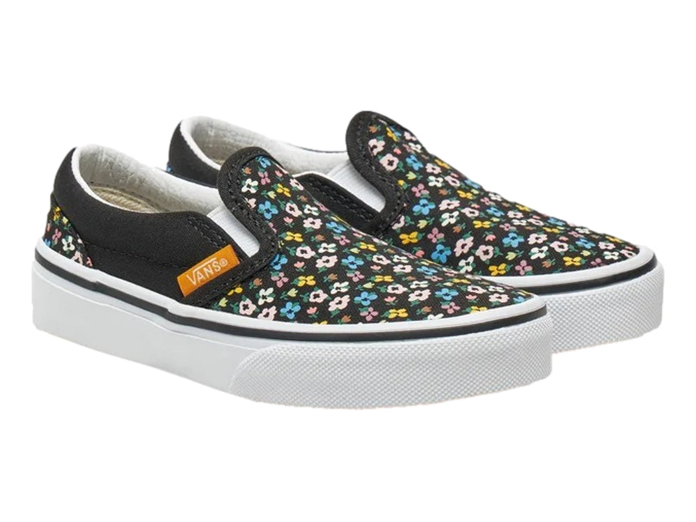 Tenis Vans slip-on negros con estampado de flores multicolores y suela blanca.