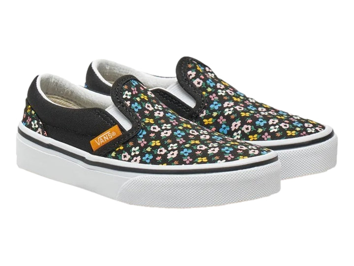 Tenis Vans slip-on negros con estampado de flores multicolores y suela blanca.
