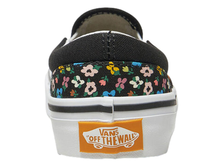 Tenis Vans slip-on negros con estampado de flores multicolores y suela blanca.