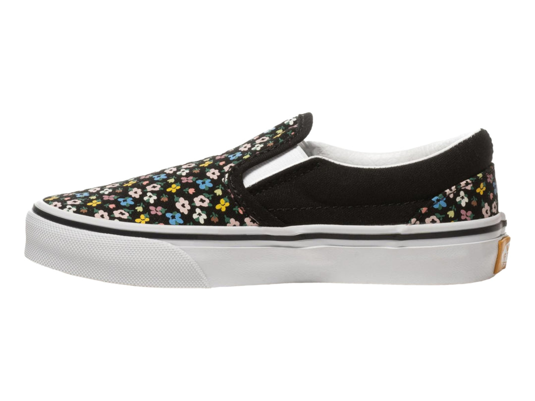 Tenis Vans slip-on negros con estampado de flores multicolores y suela blanca.